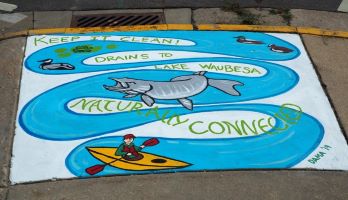 Storm drain mural featuring a person on a kayak and a fish